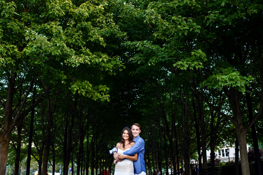 An adorable couple walk the tree lined walkway in battery park for their engagment session.